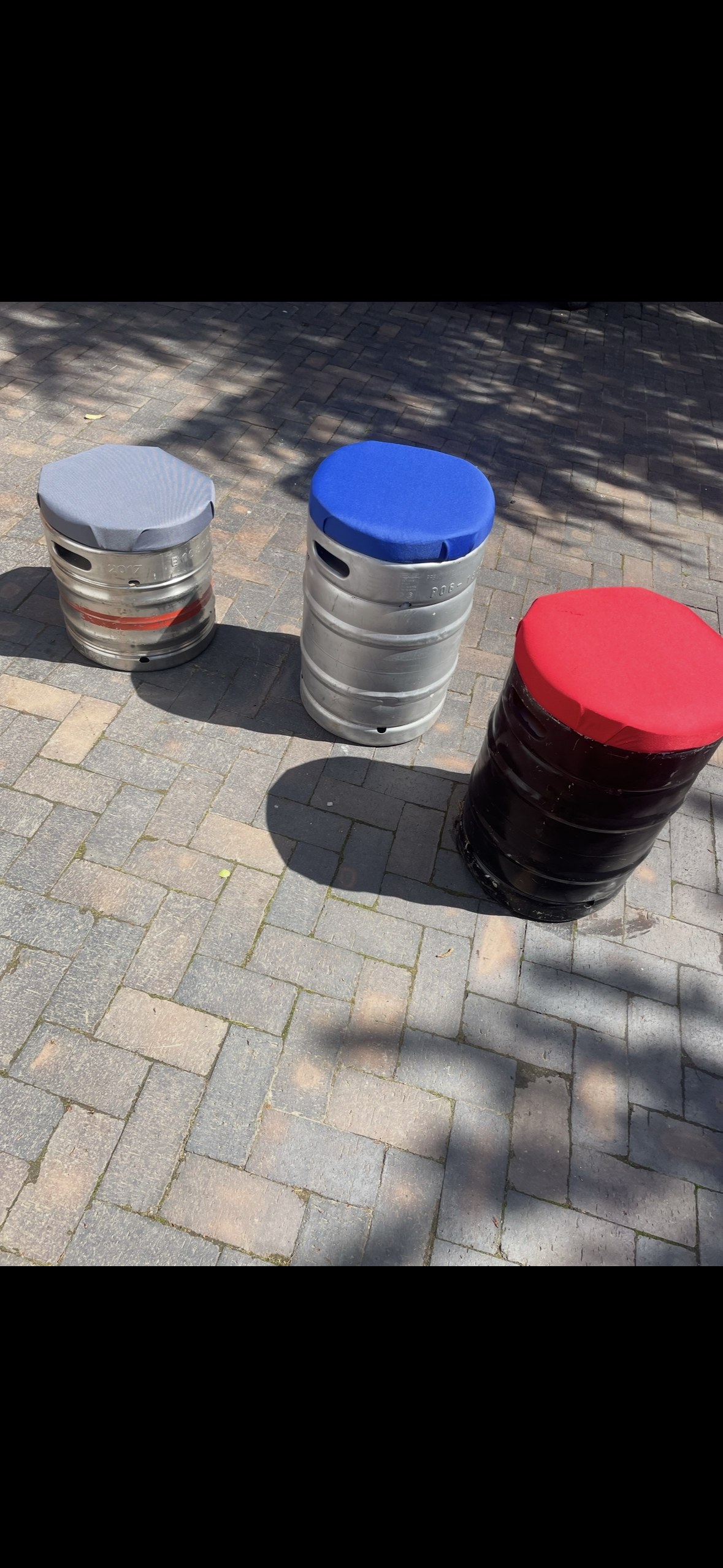 Blue, grey and red keg seats on paving